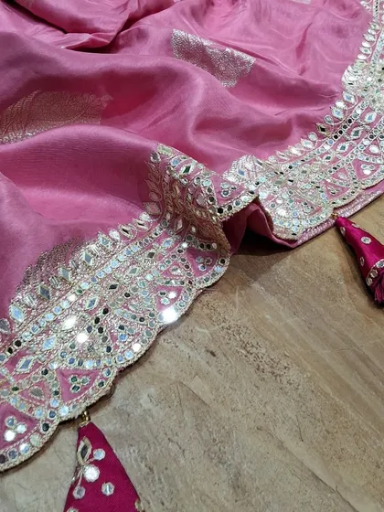 It's all in the details. This close-up shows the stunning Gota Patti and mirror work border on one of our festive pink sarees. The delicate tassels add a playful touch, making it a perfect choice for weddings and celebrations.