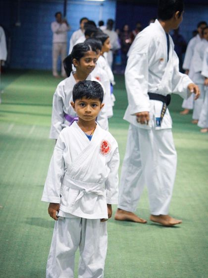 A young student in his white gi stands with a look of determination, ready for his belt grading examination.