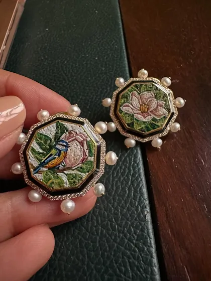 A closer look at the asymmetrical earrings worn by Radhika Ambani, featuring a bird and a magnolia blossom.