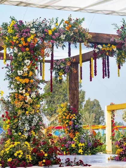 A beautiful garden wedding mandap, with pillars spiraled with a rainbow of fresh flowers, creating a stunning focal point for the ceremony.