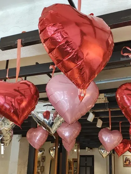 A close-up view of the red, pink, and silver heart balloons. Using different shades of the same color family adds depth and visual interest to the overall decoration scheme.