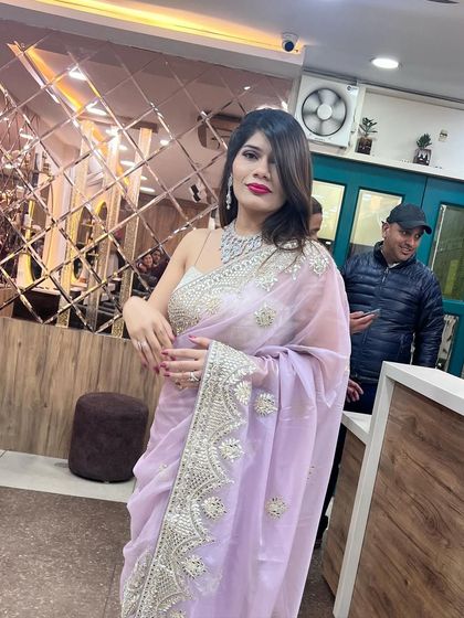 A client looking classy and glamorous in a lavender saree, with soft side-swept hair and bold makeup.