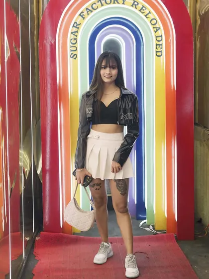 A guest posing at the iconic rainbow archway at Sugar Factory Reloaded. It's one of the most Instagrammable spots in the club.
