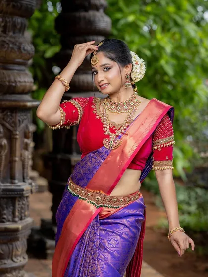 A full-length bridal portrait showcasing the saree and jewelry against the backdrop of our stone pillars.