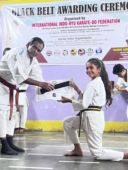 The official Black Belt Awarding Ceremony. Here, a senior master presents Lekissha with her belt and certificate, a formal recognition of her achievement in front of her peers.