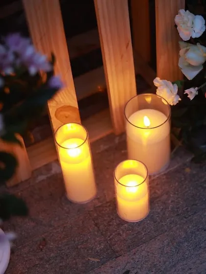A collection of pillar candles in glass holders, placed alongside fresh flower arrangements, provides soft, ambient lighting for a perfect date night.
