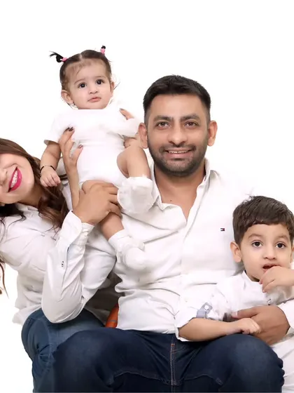 A happy family of four posing for a classic studio portrait against a white background.