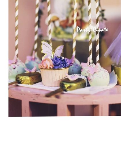A close-up of the themed desserts. These cupcakes and cakesicles are adorned with delicate, edible butterflies to perfectly match the enchanted fairy theme.