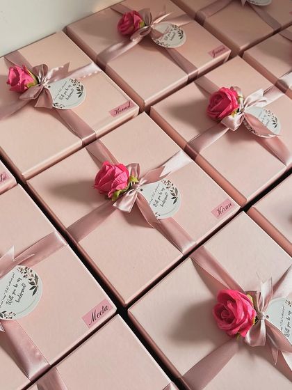 A lineup of our beautifully wrapped bridesmaid boxes, each personalized with a name sticker and a delicate artificial rose. It's all in the details!