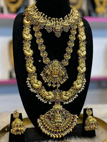 This bridal set features beautiful peacock motifs throughout the choker and the long necklace, studded with ruby and emerald colored stones.