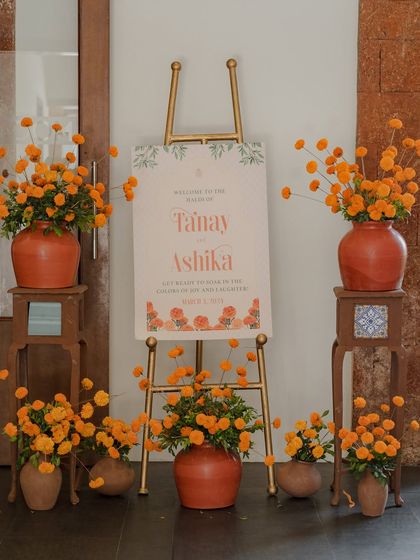 The welcome easel for the Haldi, surrounded by terracotta pots filled with bright orange marigolds.