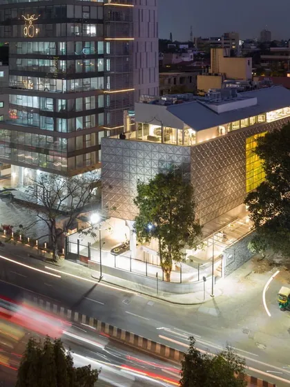 This is the Museum of Art & Photography (MAP) in Bengaluru, a cultural landmark we designed to be a 'tanki' or container for art. The building's stainless steel facade reflects the city's energy, creating a dynamic presence in the urban landscape, especially as dusk settles and the structure glows from within.