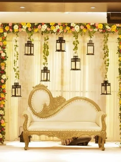 I love creating reception stages that feel both elegant and warm. Here, a classic white and gold chaise lounge is framed by colorful floral pillars and delicate hanging lanterns, creating a romantic and picture perfect setting for the happy couple.