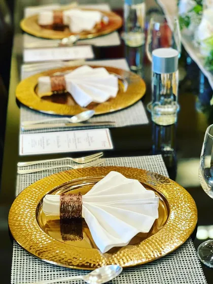 A close-up of our formal place setting, complete with gold-rimmed plates, fan-folded napkins, and a printed menu for the guests.