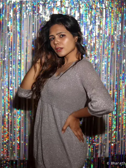 A fun and glamorous shot of a model in a sparkly silver dress against a tinsel backdrop. Perfect for party wear or festive lookbooks.