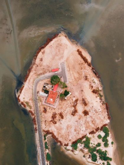 A top-down drone photograph of the Shri Ram Temple at Dhanushkodi, showing its isolated location at the tip of the land.