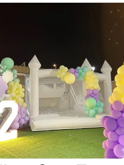 An outdoor setup of our white bouncy castle, decorated with a custom balloon garland. We can tailor the balloon colors to match your party's theme perfectly, creating a beautiful and fun focal point.