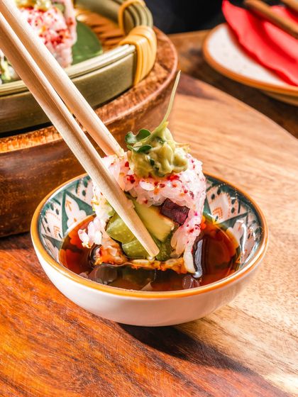 Savor the intricate craftsmanship in every bite. Our sushi roll, dipped in soy sauce, is a delicate harmony of fresh ingredients and rich flavors, showcasing true culinary artistry.