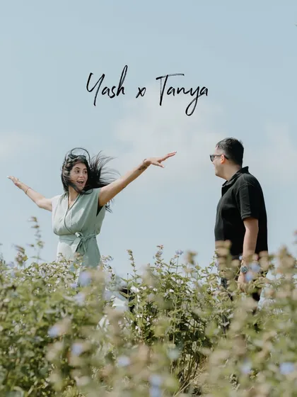 A fun and playful moment in a field of wildflowers. Her joyful, outstretched arms and his smiling gaze create a candid photo that is full of life and happiness.