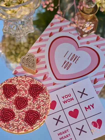 A flat lay of the custom stationery and decor elements on a mirrored tabletop, reflecting the sky. This includes a beaded coaster and a wooden block stamp.