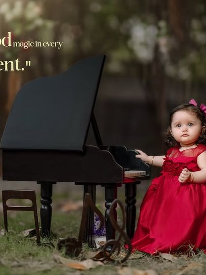 Childhood magic in every moment. A little girl in a red dress plays the piano in an enchanted forest setting.