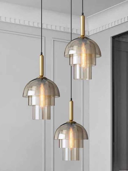A cluster of three tiered glass pendants hanging over a dining table. Grouping them at different heights creates a dynamic and stylish installation.