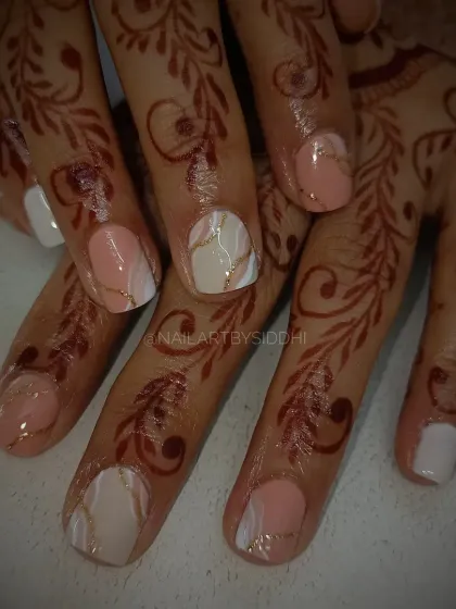 This elegant design for shorter nails features a mix of solid white and a soft pink marble with delicate gold lines, perfectly complementing the client's henna.
