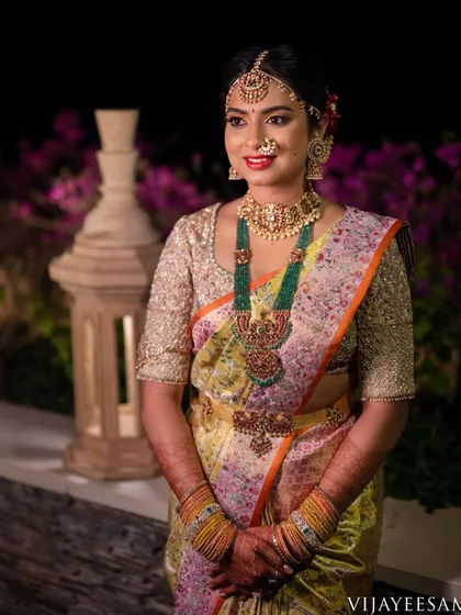 A bride's reception look featuring a pastel-colored saree. Her custom blouse is heavily embroidered with gold thread, adding a touch of glamour to the soft-hued saree.