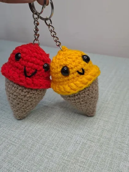 A pair of smiling ice cream cone keychains in red and yellow. They are a perfect summer accessory.
