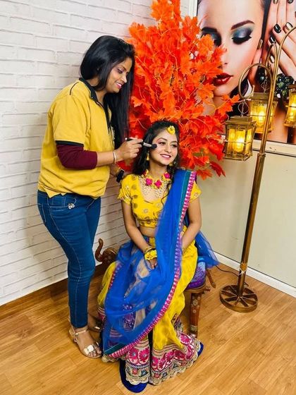 A student practicing a Haldi look on a smiling model in our academy. This behind-the-scenes shot shows the positive and hands-on learning environment we foster.