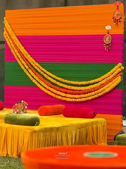 The traditional marigold garland swag against the colorful draped backdrop, a classic element in Indian celebrations.
