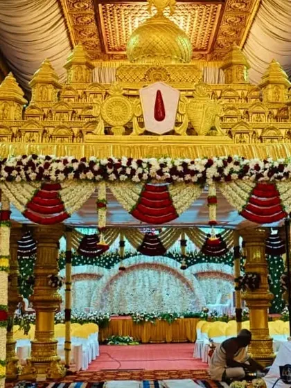 For a truly royal wedding, we designed this grand Muhurtham mandapam, inspired by traditional temple architecture. The intricate gold structure, combined with red and white floral garlands, creates a sacred and opulent space for the main ceremony.