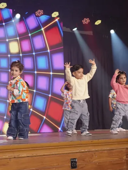 A young performer takes center stage, arms raised in a moment of pure expression. This shot captures the individual confidence that blossoms within our group dance activities.