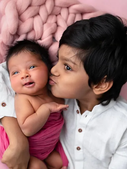 A gentle kiss from a big brother to his newborn sister. These unscripted, tender moments are what make sibling portraits so deeply meaningful.