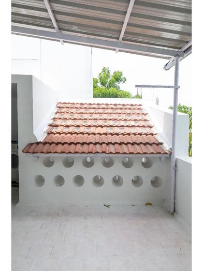 The rooftop terrace features a wall with circular openings, another innovative technique used in this project to manage light and airflow without conventional windows.