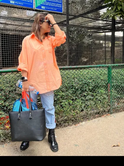 This shows the versatility of one outfit. By swapping the heels for chunky black boots and adding a large tote bag, the same peach shirt and jeans are transformed into a practical and stylish look for a day out.