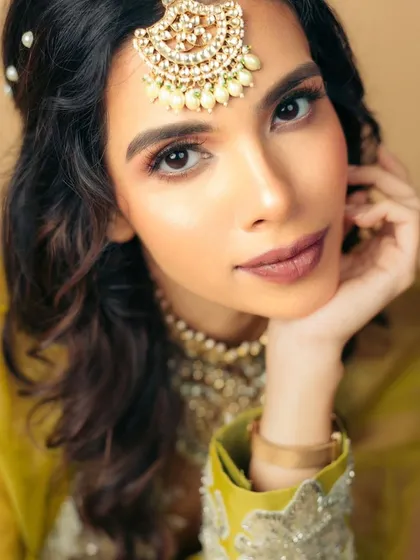 This shot highlights the beautiful contrast between the soft eye makeup and a slightly deeper nude lip, creating a balanced and sophisticated bridal look.