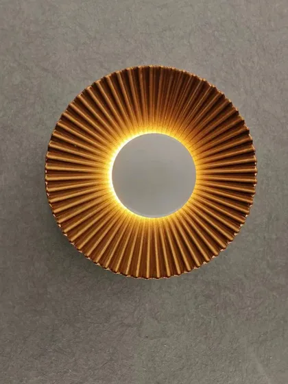 A pleated, sun-like wall sconce that creates a beautiful halo of light. This fixture adds texture and warmth to any wall.
