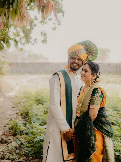 A wide shot of the couple in a serene, natural environment. Their happy expressions and traditional outfits create a timeless and beautiful image.