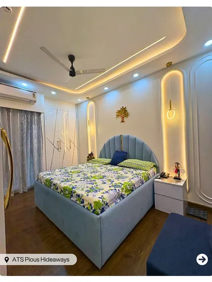 A dreamy bedroom with a beautiful blue upholstered bed and intricate wall molding with integrated backlighting. The design feels both modern and romantic.