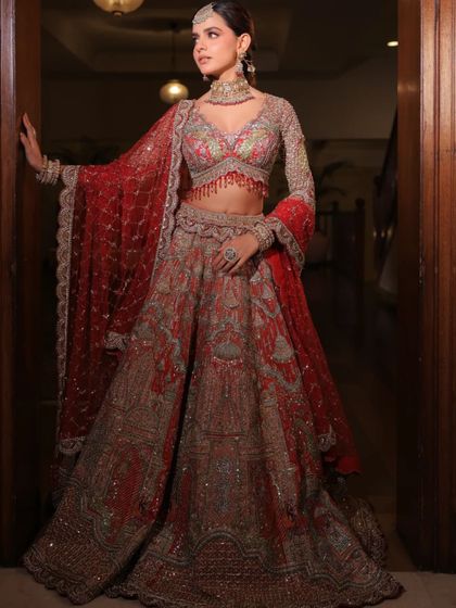 A grand entrance in a heavily embroidered red and silver lehenga. The full-sleeved blouse and the detailed skirt are perfect for a bride wanting a majestic look.