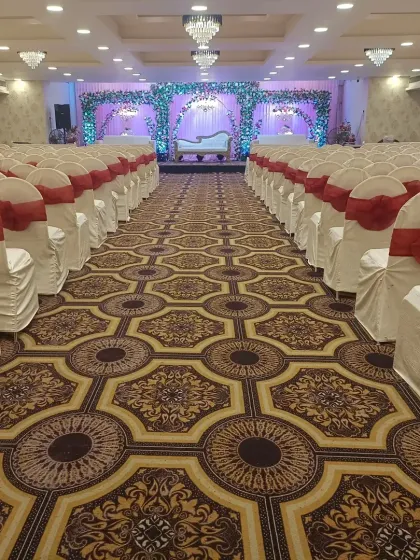 A long view of a banquet hall aisle, lined with chairs covered in white and red. This classic color combination is perfect for weddings and receptions.