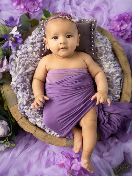 A little flower in a purple garden. This baby is wide-eyed and curious, taking in all the beautiful colors of her floral-themed photoshoot.
