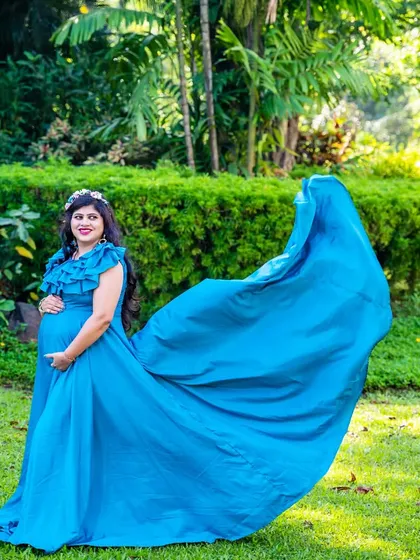 A solo portrait of the mom-to-be in a flowing blue gown, creating a striking image against the green garden backdrop.