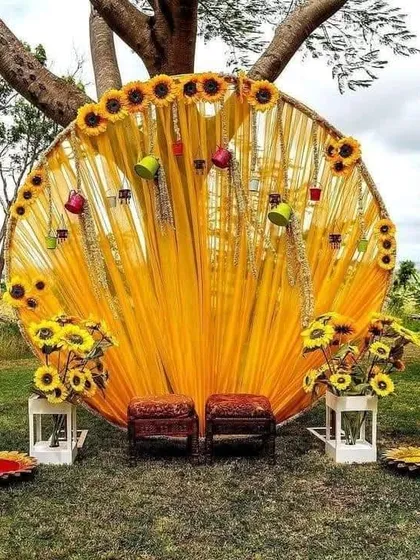 For a unique Haldi or Mehendi, I design vibrant outdoor setups. This circular backdrop with bright yellow drapes and sunflowers creates a cheerful and picturesque spot for your ceremony.