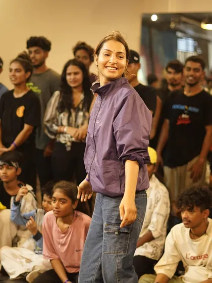 A smiling b-girl in the crowd, watching the battles unfold. We foster a supportive and positive environment for all attendees.