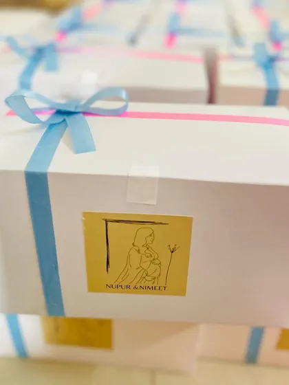 A custom-packaged baby shower return favor. The white box is adorned with a personalized sticker and ribbons, creating a sweet and memorable gift for guests.