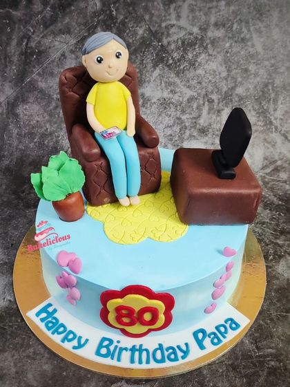 Celebrating a wonderful 80th birthday for a beloved Papa. This cake depicts him relaxing in his favourite chair and watching TV, a personal scene created with fondant.