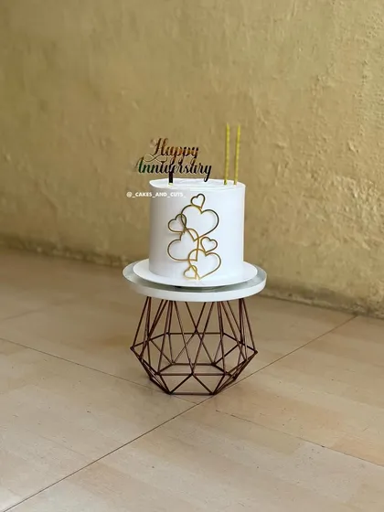A clean and modern anniversary cake with a heart design and a "Happy Anniversary" topper.