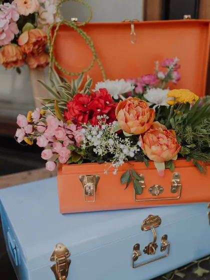 A creative floral arrangement inside a vintage-style painted trunk. We love using unconventional props to create unique decor moments.